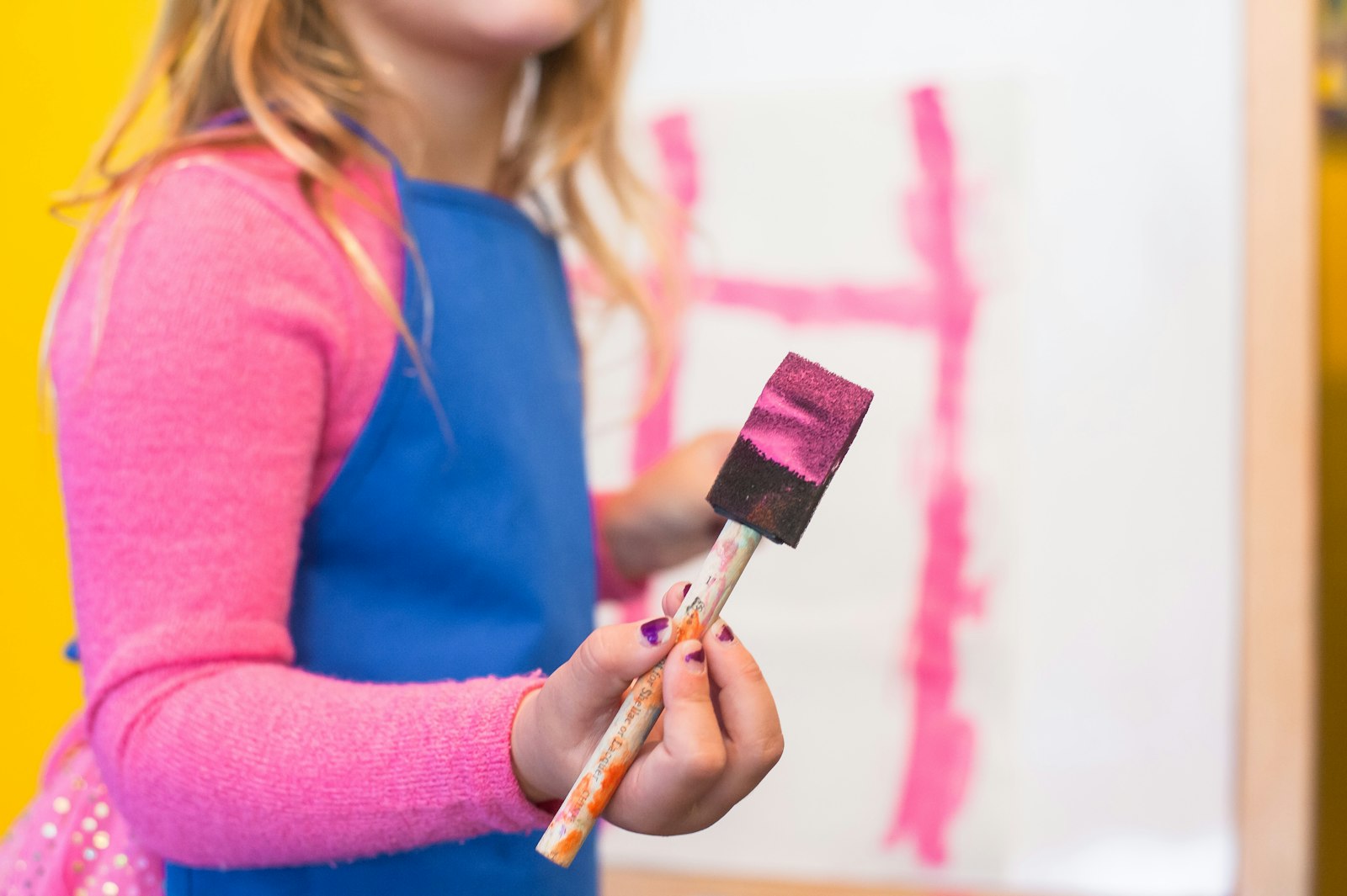 Child painting with a sponge brush at Kaleidoscope Arts Studio